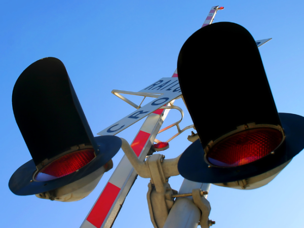 A railway crossing with warning lights and gates.