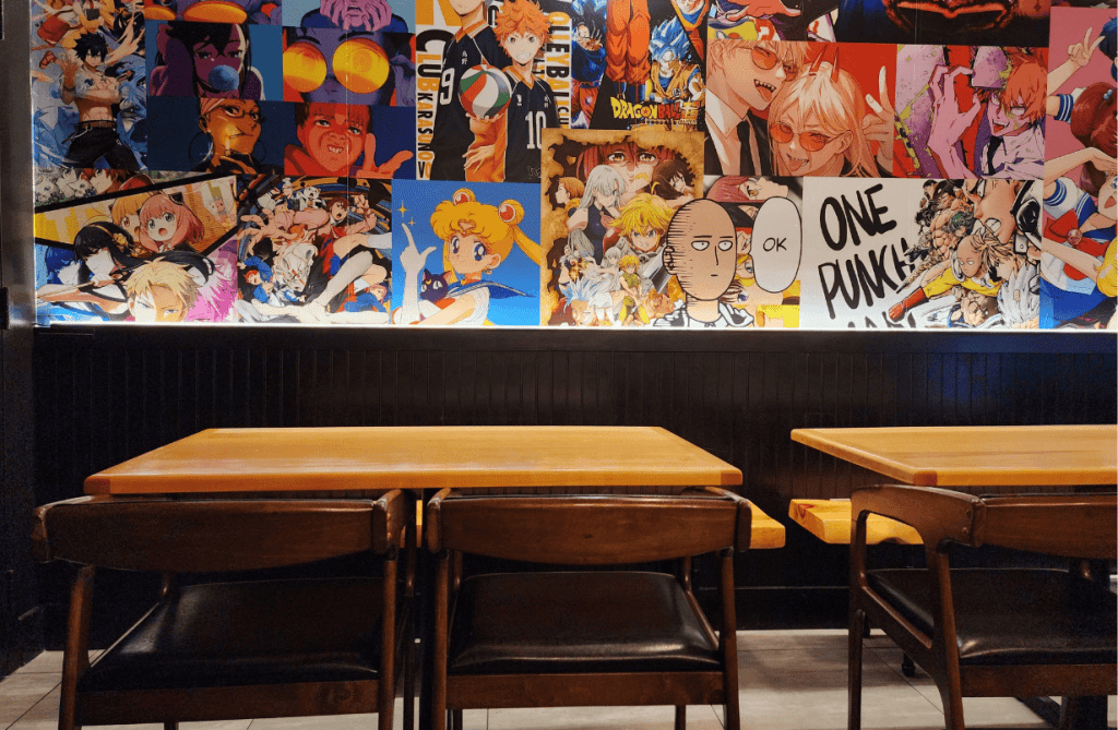 Interior view of Umami Kid in Uptown Saint John featuring bold anime-themed wall art and wooden tables for an energetic, modern dining atmosphere.