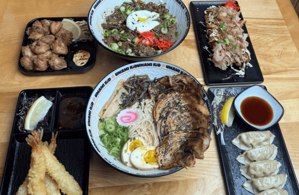 A table filled with ramen, gyoza, karaage, tempura, and donburi at Umami Kid in Uptown Saint John, showcasing the restaurant’s authentic Japanese menu.
