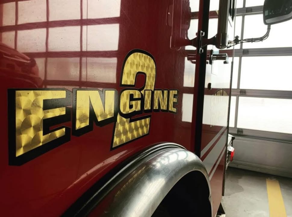 Saint John firefighters outside a mobile home with smoke coming from it.