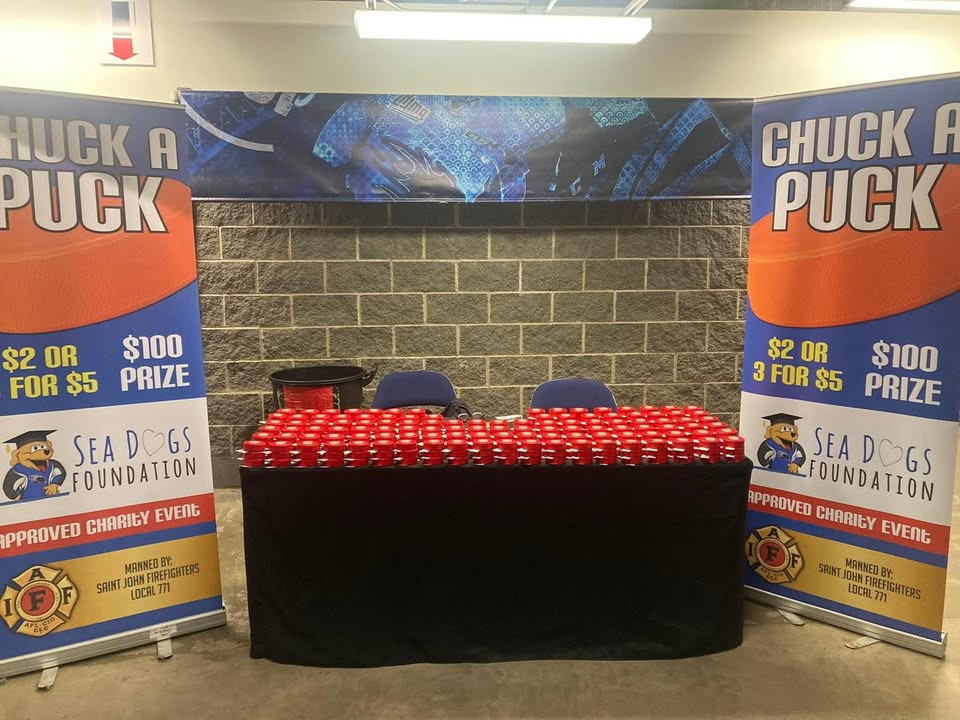 Saint John Firefighters holding pucks for their Chuck-a-Puck fundraiser at a Sea Dogs game.