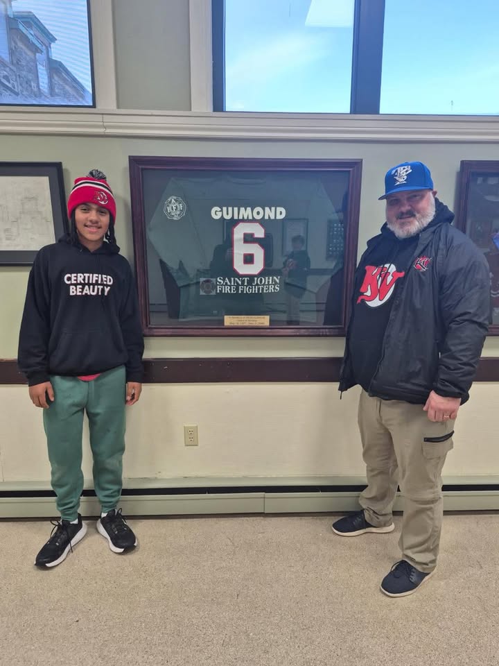 Coach Josh Guimond and his son Jack pose with the memorial jersey of firefighter Omer Guimond.