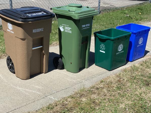 Three garbage bins placed at the curb for collection.