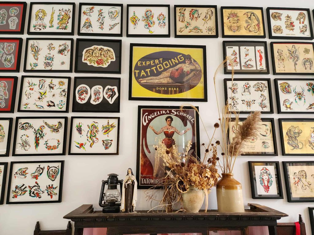 A gallery wall of framed traditional tattoo flash designs displayed inside 162 Princess Street Tattoo in Uptown Saint John.
