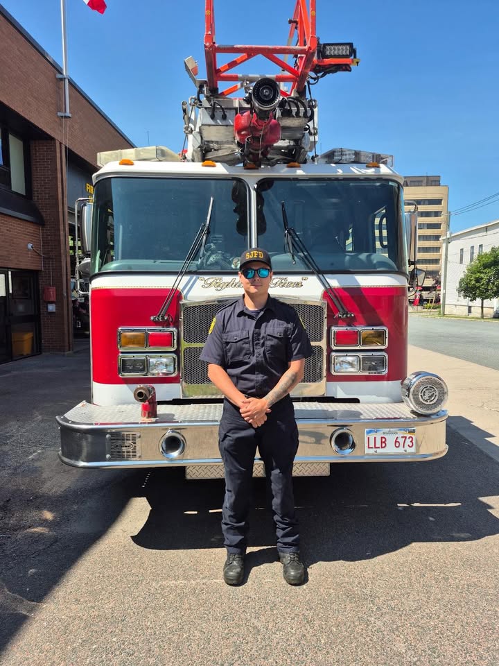 Aiden Villareal standing in front of a Saint John fire truck
