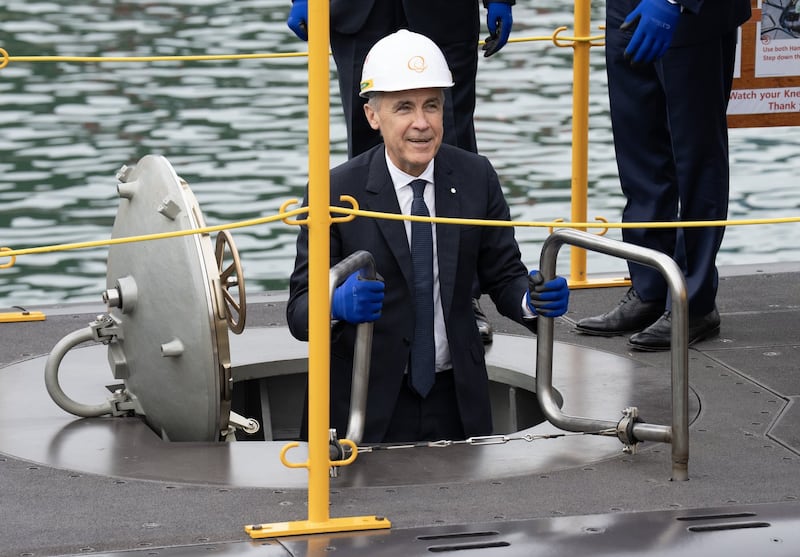 Prime Minister Mark Carney climbs down a ladder into a submarine
